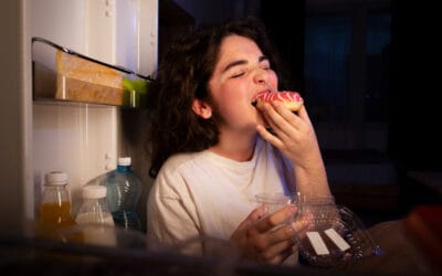 A woman is eating a donut in the kitchen